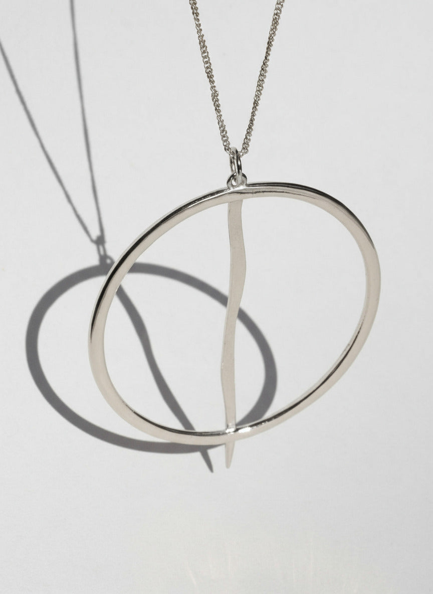 Silver necklace with a unique pendant on a light gray background