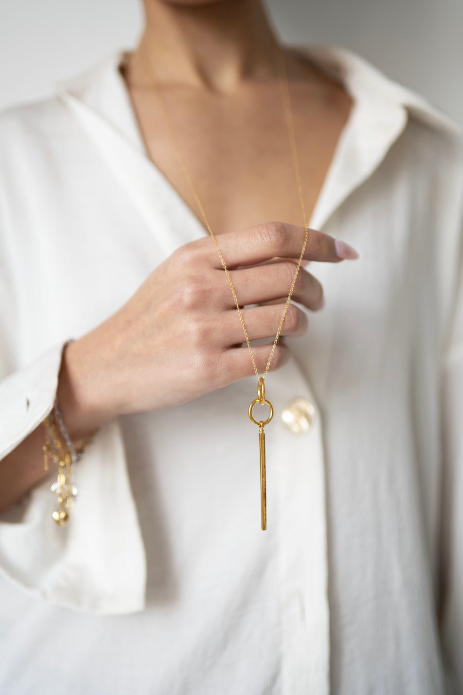 Gold long necklace held in the hand of a model