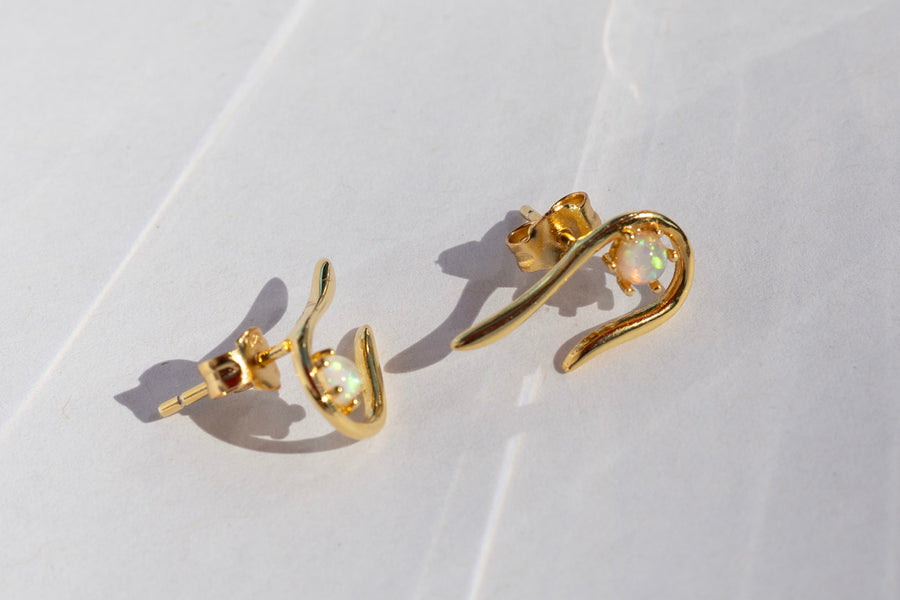 Gold earrings with opal stones on a light background