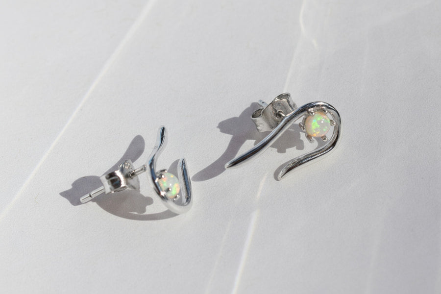 Gold earrings with opal stones on a light background