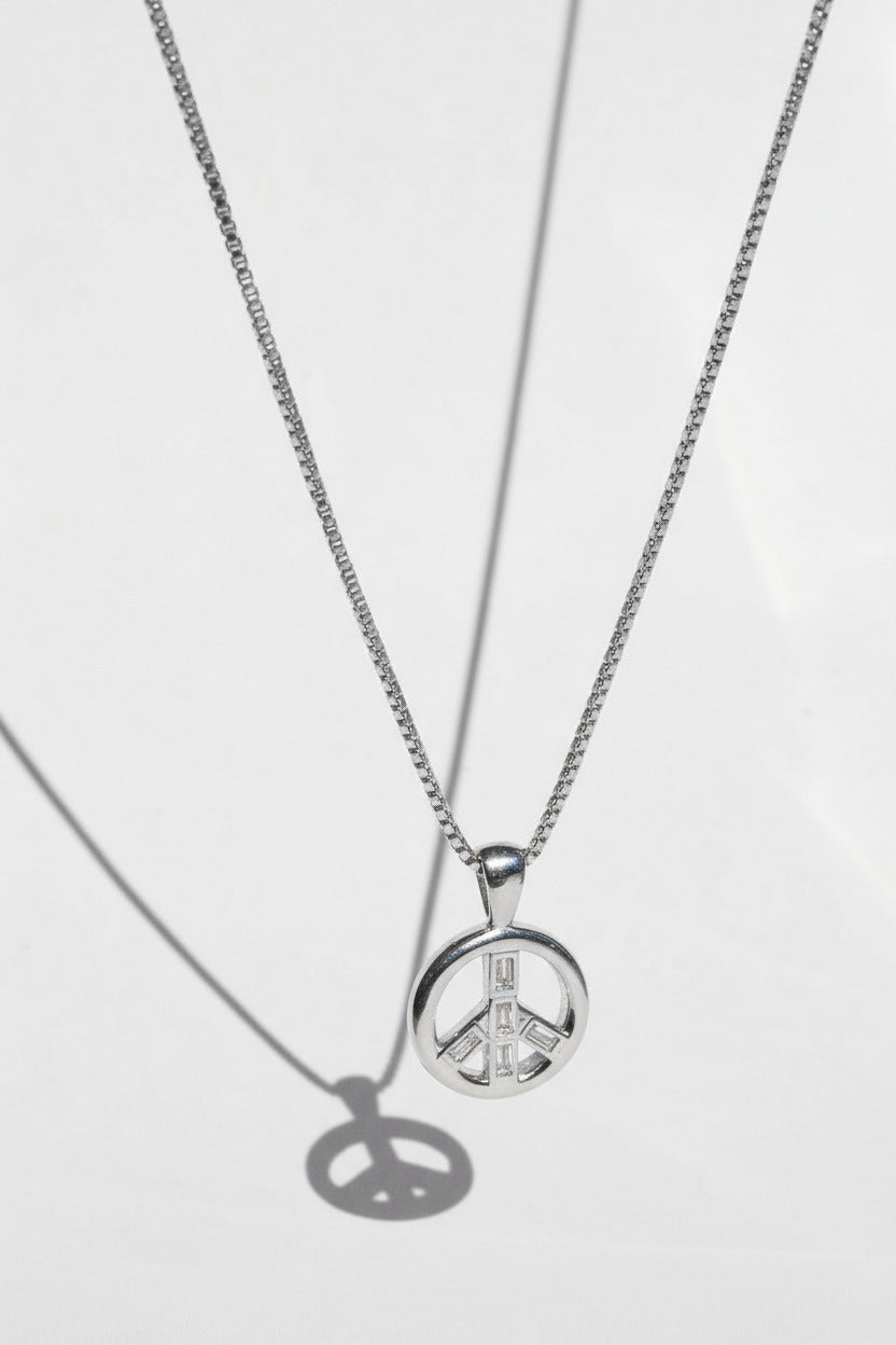 Silver necklace with a peace symbol pendant on a light gray background