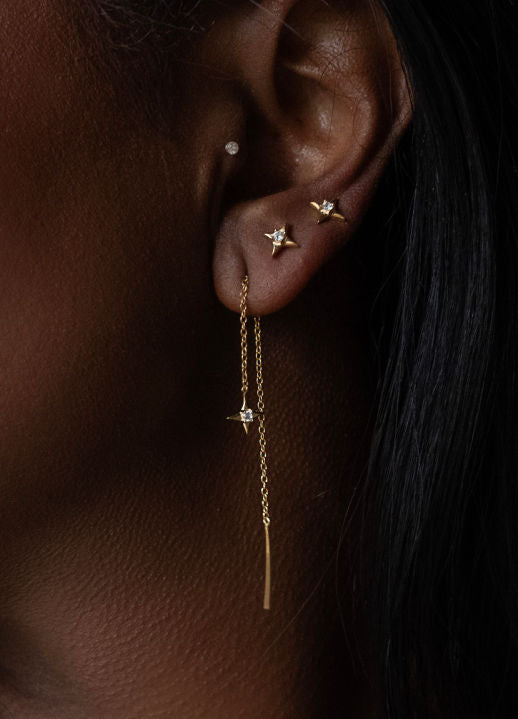Close-up of an ear with gold earrings on a dark background