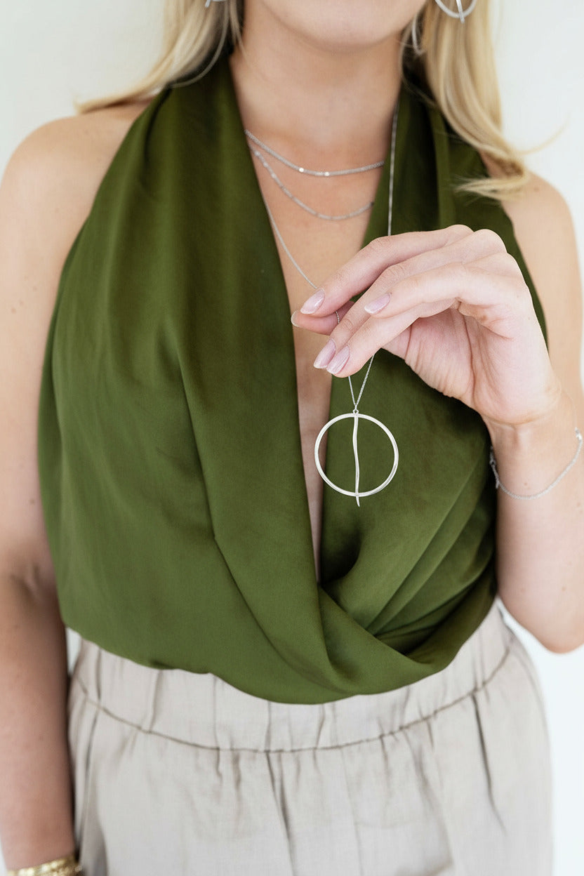 Woman wearing a green shirt and silver jewelry against a white background