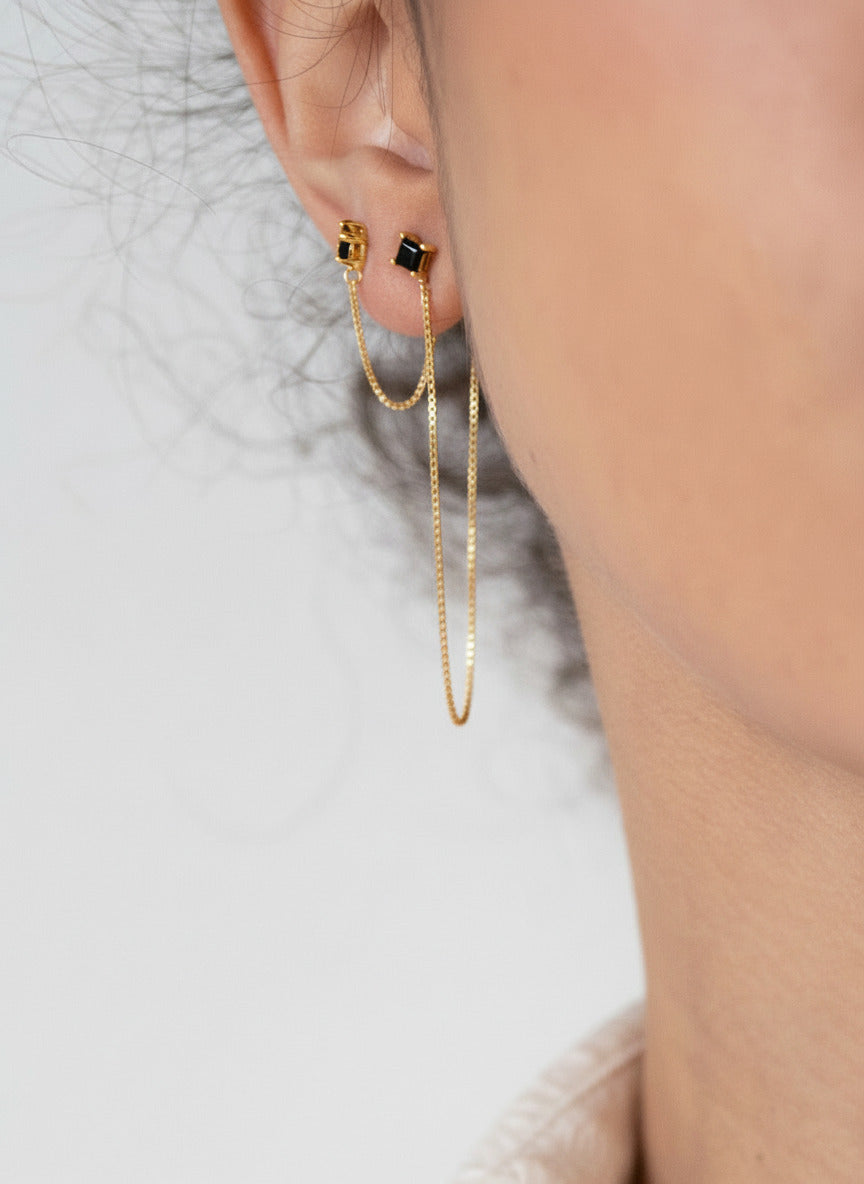 Close-up of a woman wearing gold earrings with a blurred background
