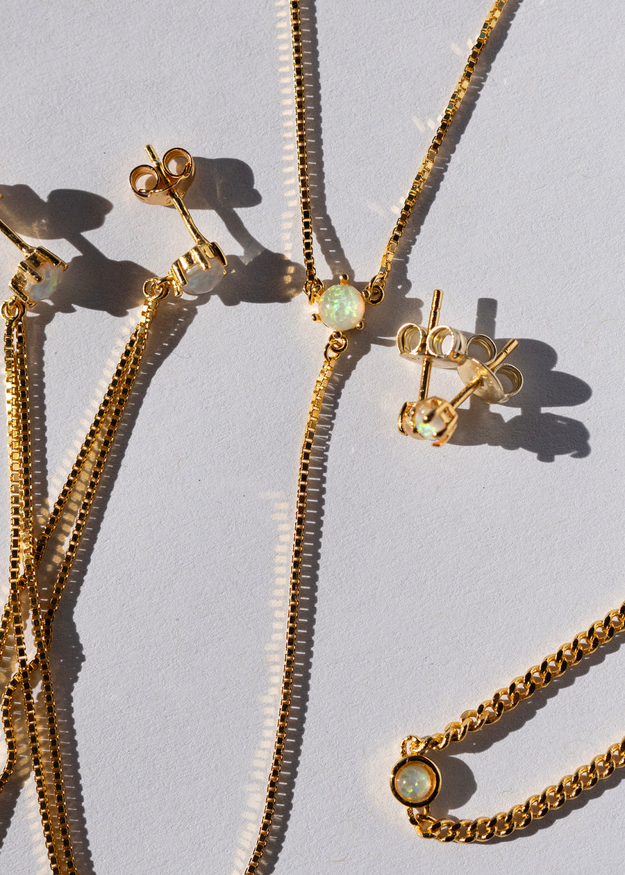 Gold jewelry set with necklace and earrings on a light gray background