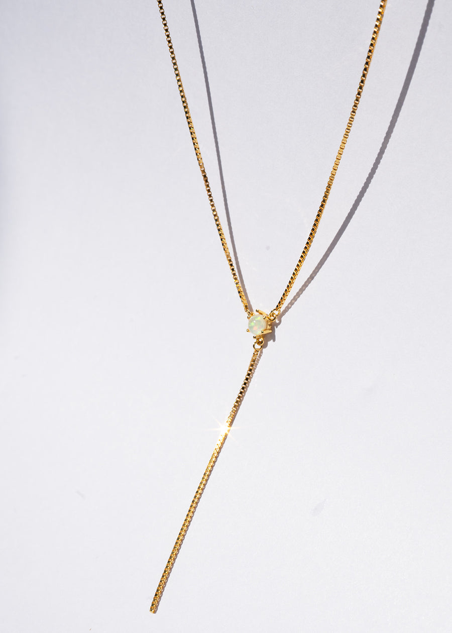 Gold necklace with a small pendant on a white background