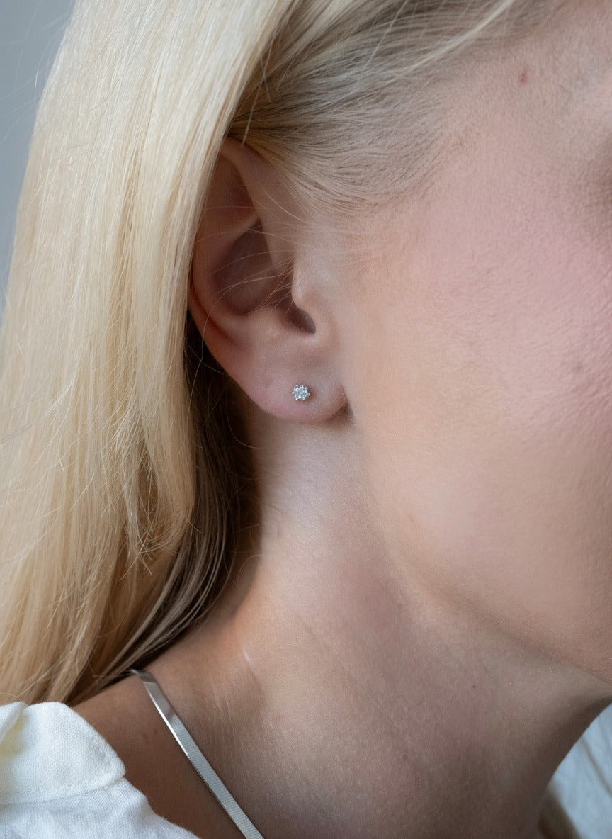 Close-up of a person wearing a gold earring with a neutral background