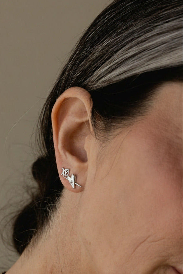 Close-up of an ear wearing a small earring with a neutral background