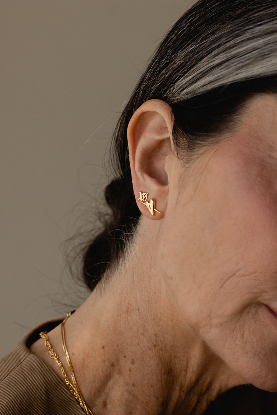 a close up photo of a woman with two gold stud earrings by designer Sarah Mulder