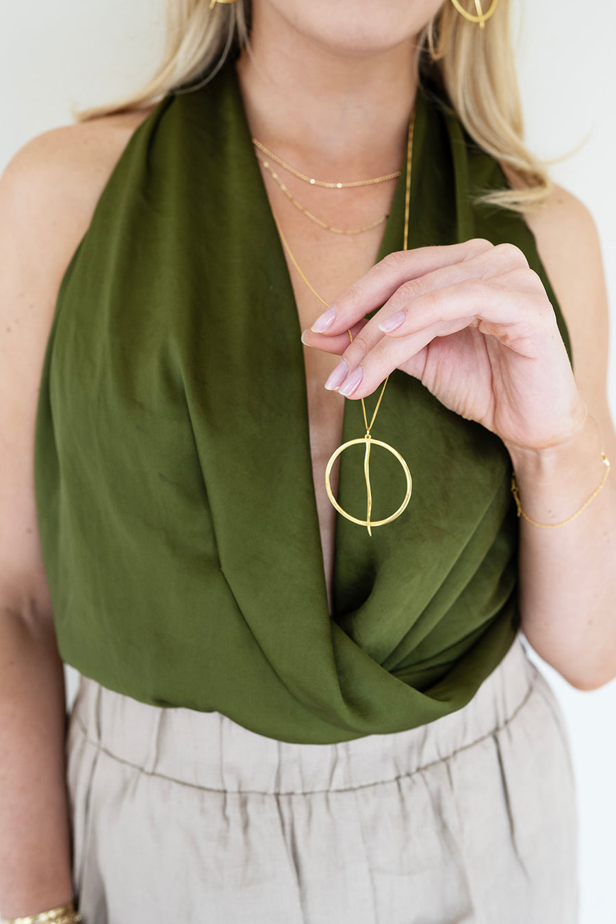 Woman wearing a green scarf and gold jewelry against a white background