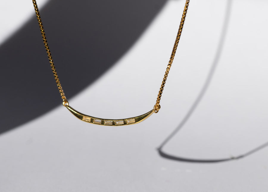 Gold necklace with a subtle design on a light gray background