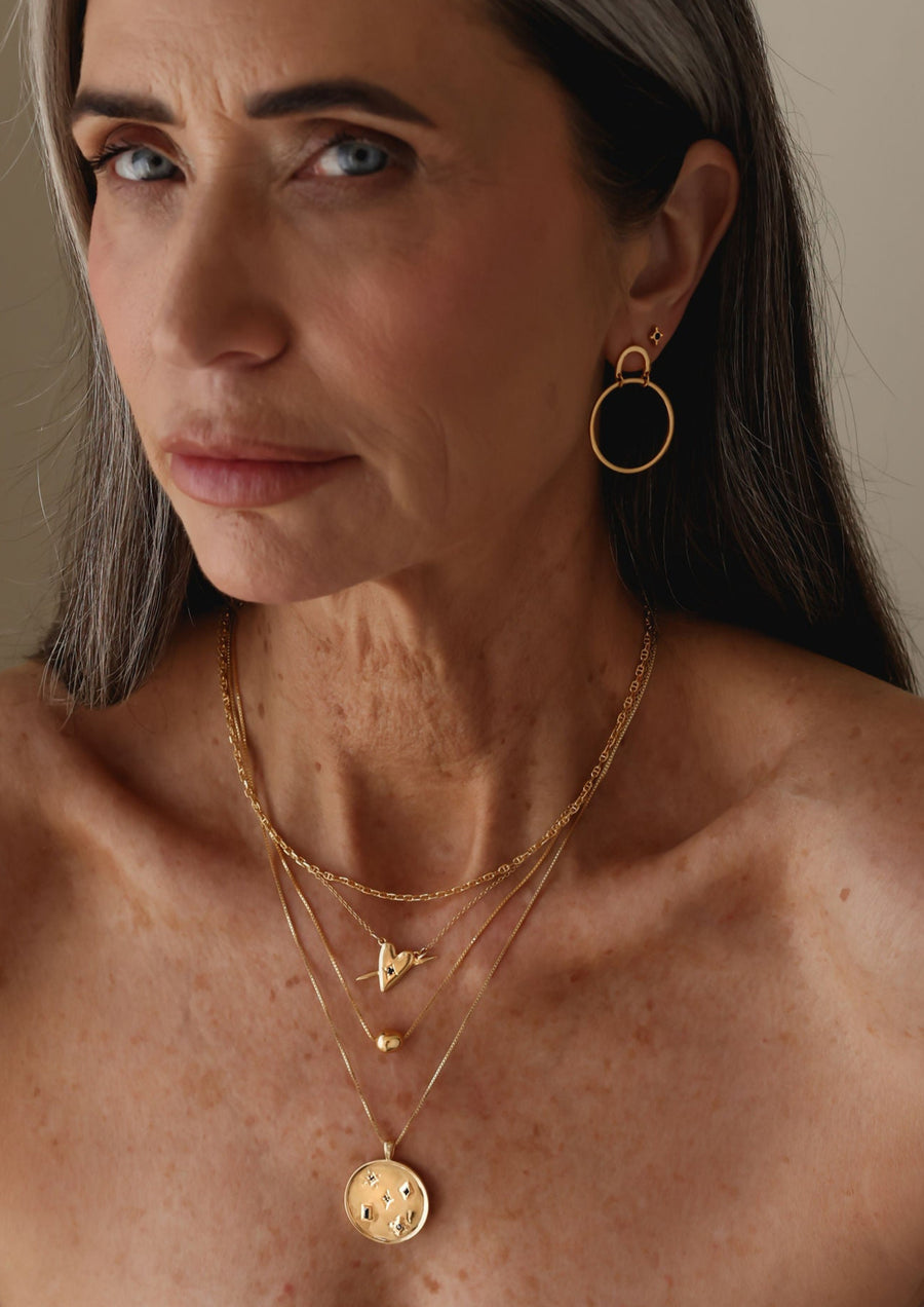 A layer of gold necklaces worn by a woman by designer Sarah Mulder Jewelry 