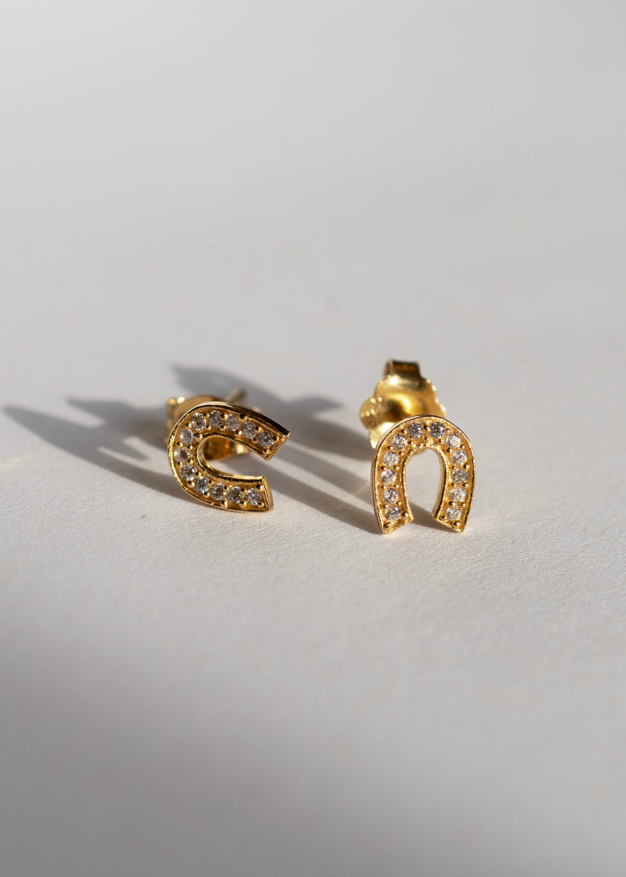Gold horseshoe studs in sunlight with cubic zirconia detail