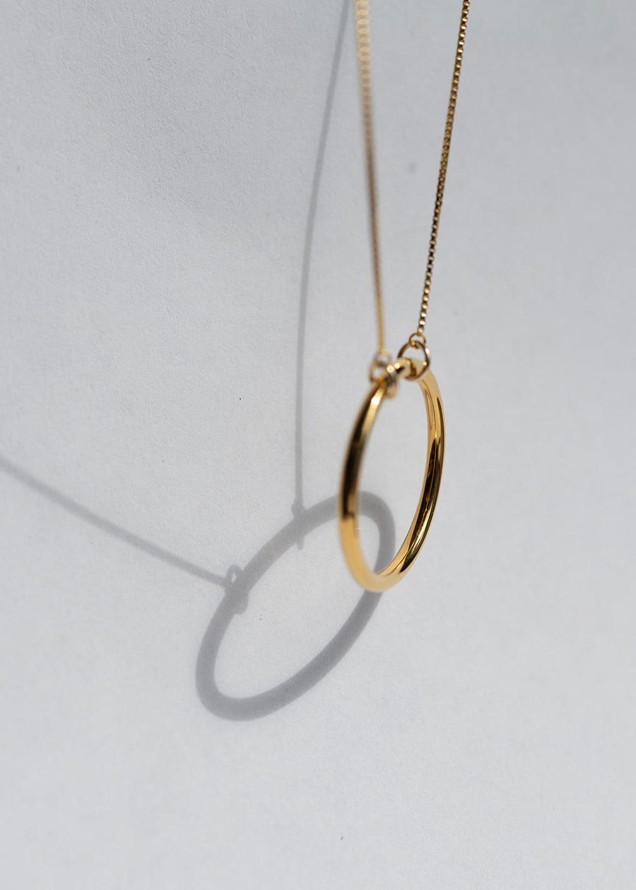 A gold necklace hung in sunlight to cast a shadow
