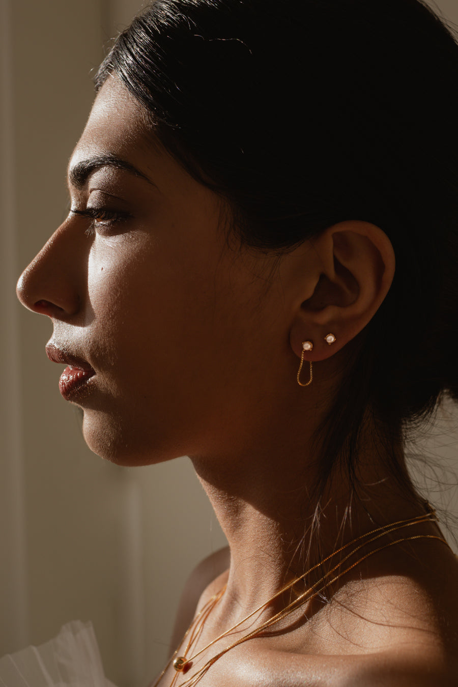 a Model wearing a layer of small pearl earrings