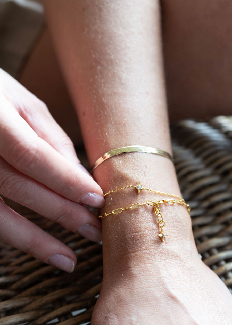 Close-up of a wrist with gold bracelets on a woven surface