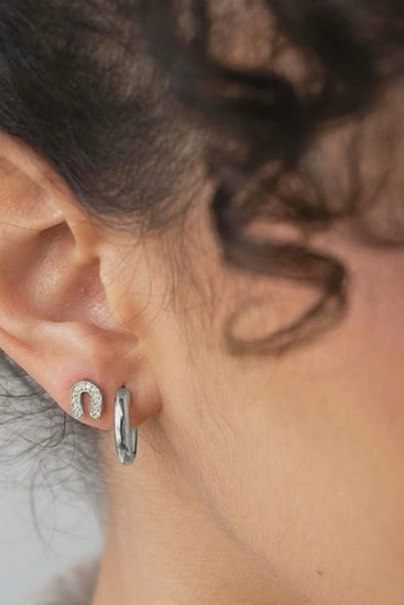 woman wearing silver horseshoe studs and hoops by designer Sarah Mulder