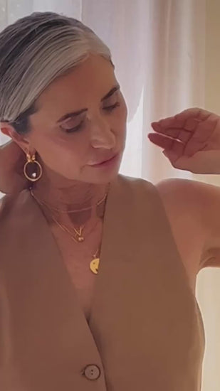 a gold pair of earrings worn by a model in a video