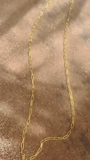 a paper clip chain necklace in gold sparkling in sunlight
