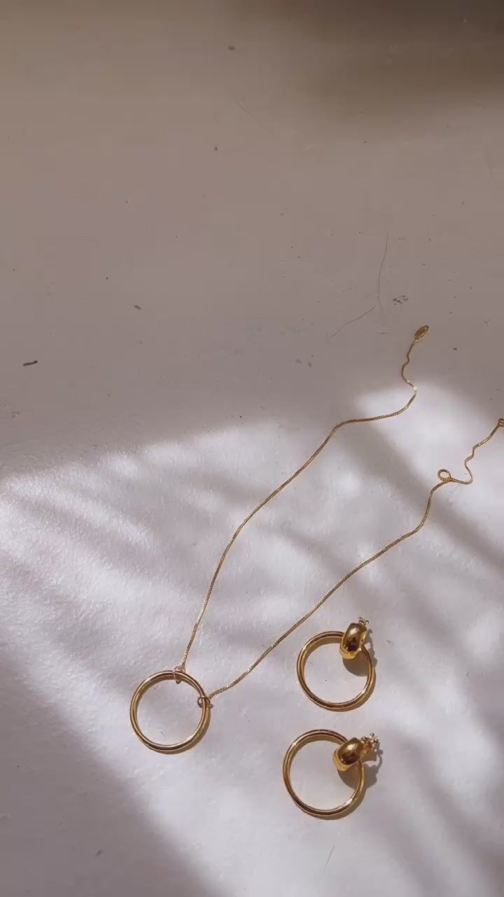 a necklace and pair of matching earrings in a sun filled room