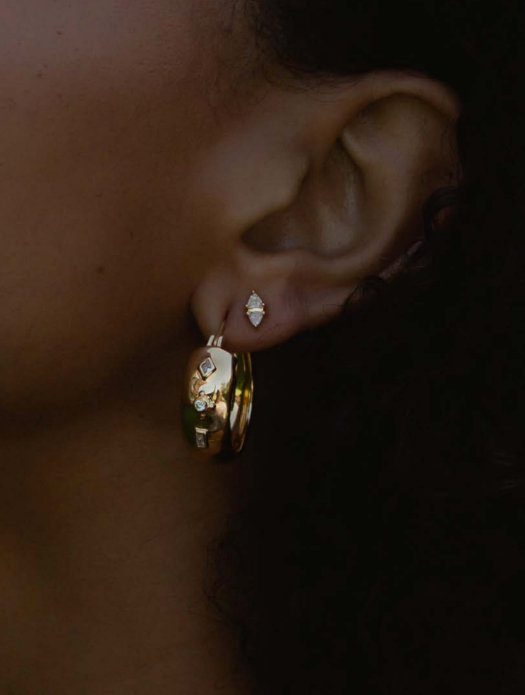big gold hoop earrings worn on an ear